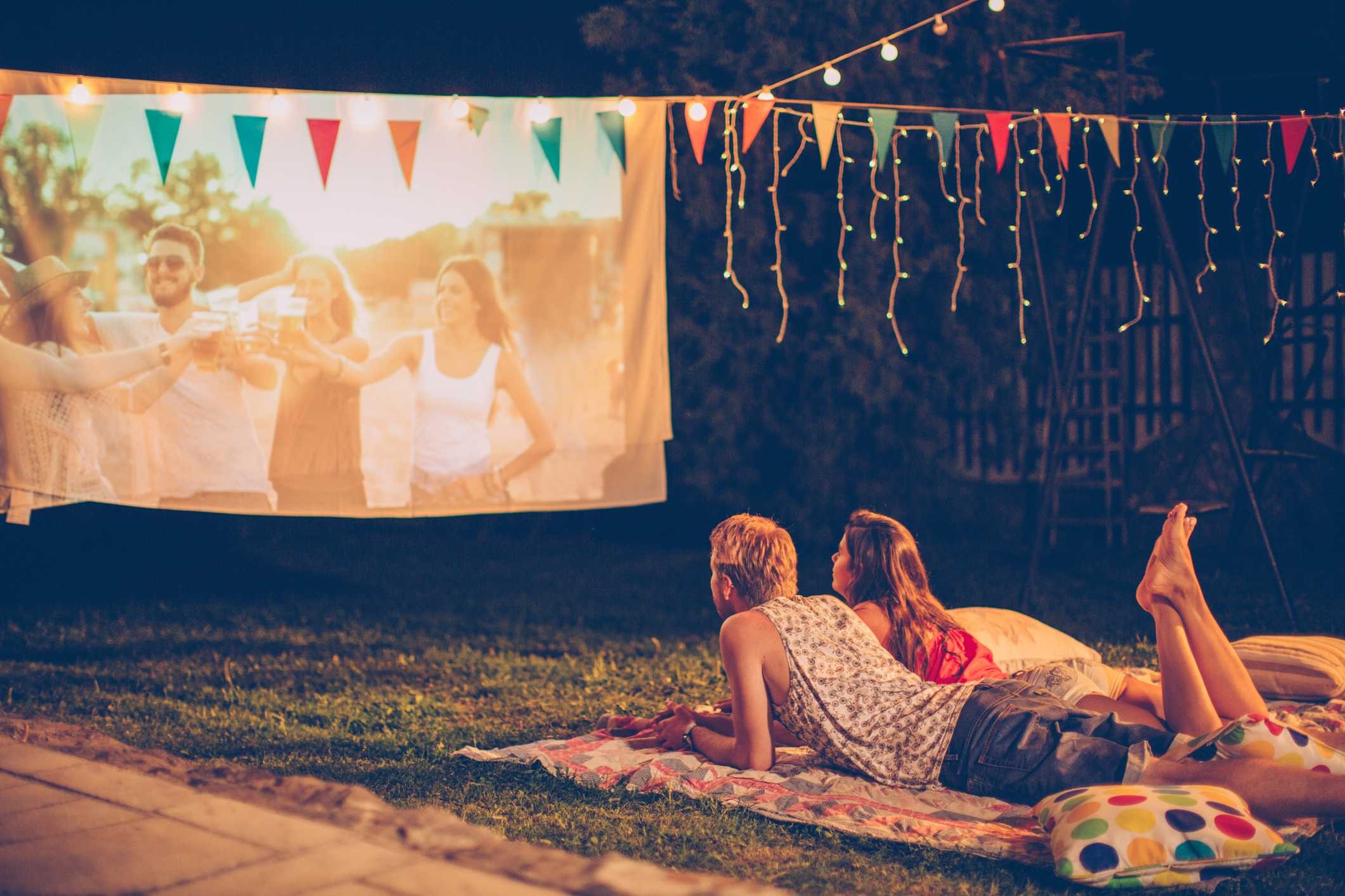 A couple watching a movie outdoors with a portable projector
