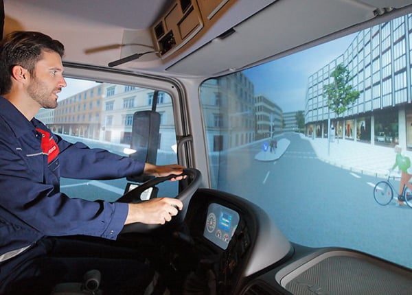 Un homme conduisant un camion virtuel sur un simulateur haptique
