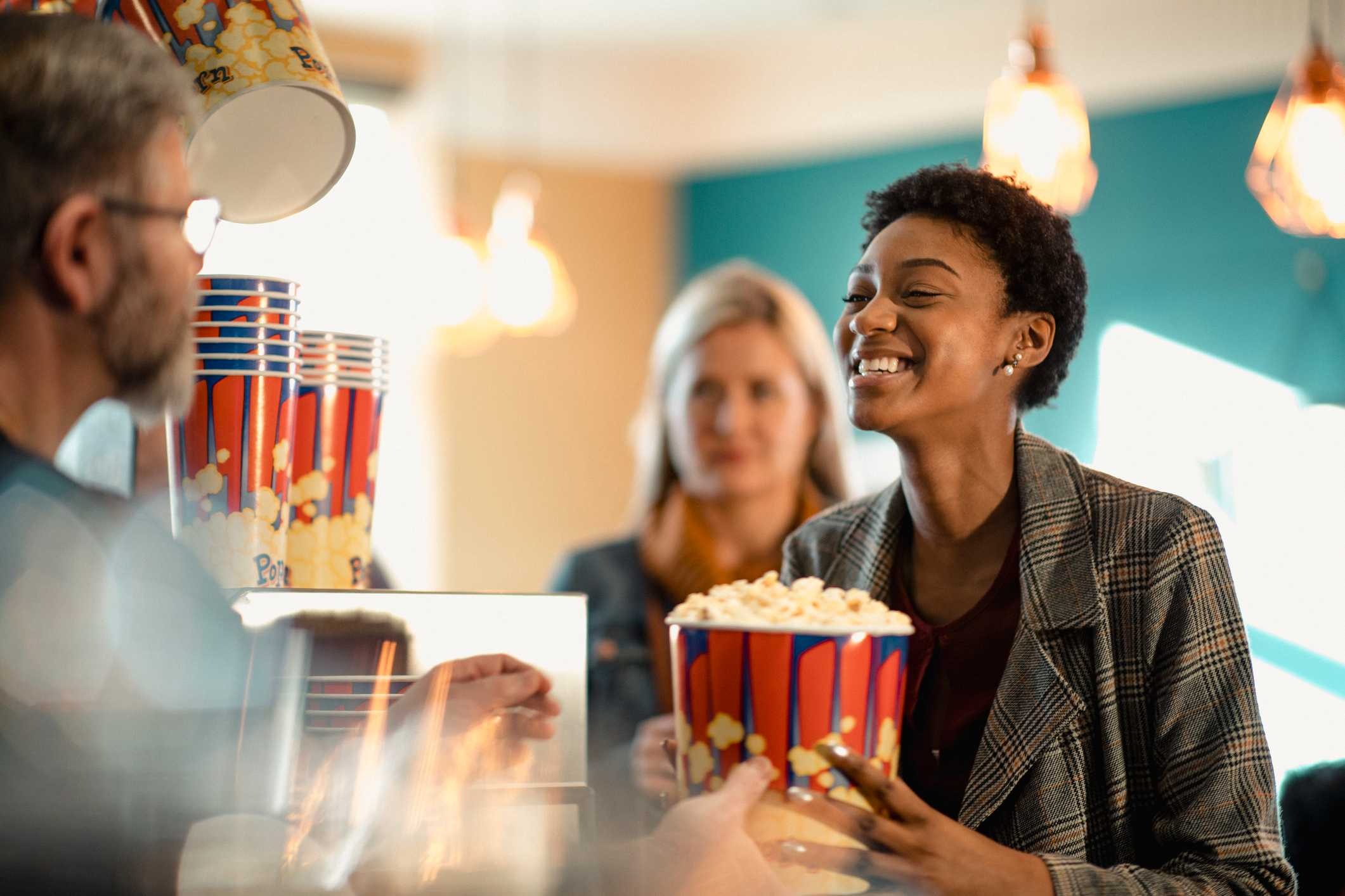 A woman smiling purchasing popcorn at the theater